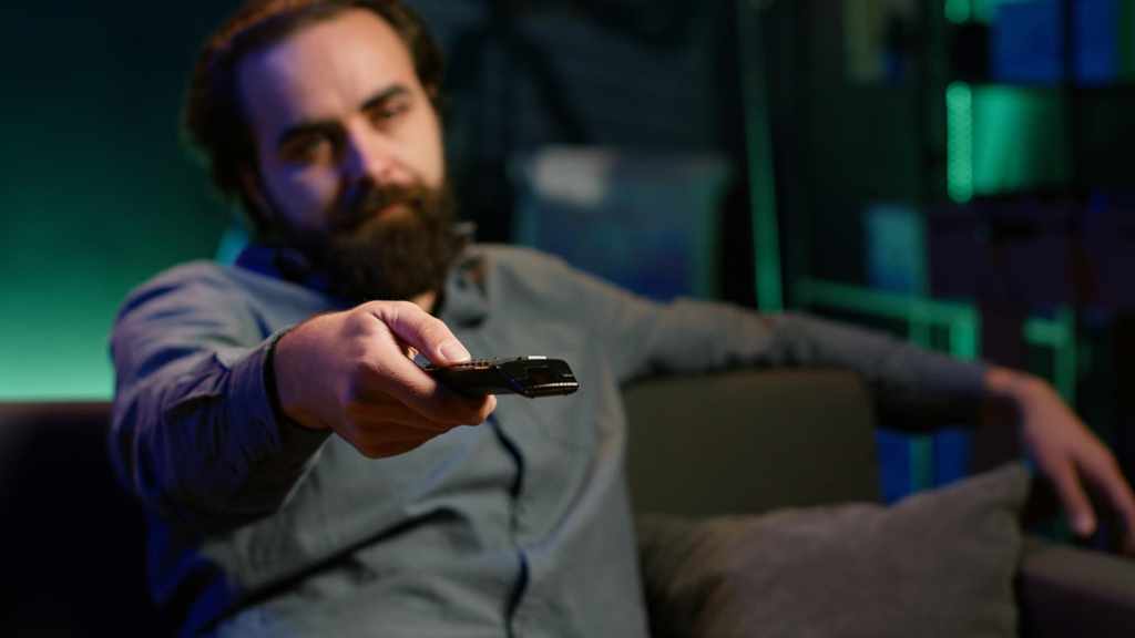 Man pointing a TV remote with a frustrated look, illustrating a Firestick remote not working.