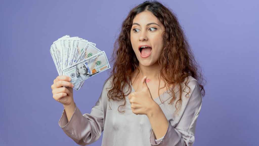 Woman holding a fan of cash and giving a thumbs up, symbolizing simple ways to make extra money